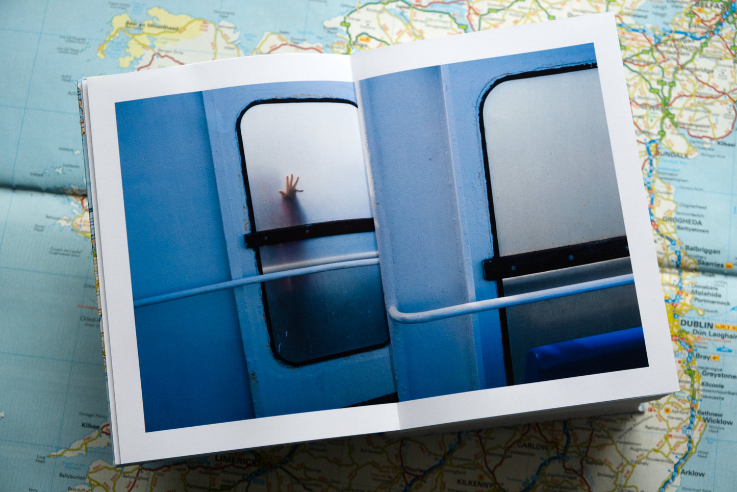 product photo of handmade photography book on Ireland showing double page spread of child's hand on window on a ferry ship