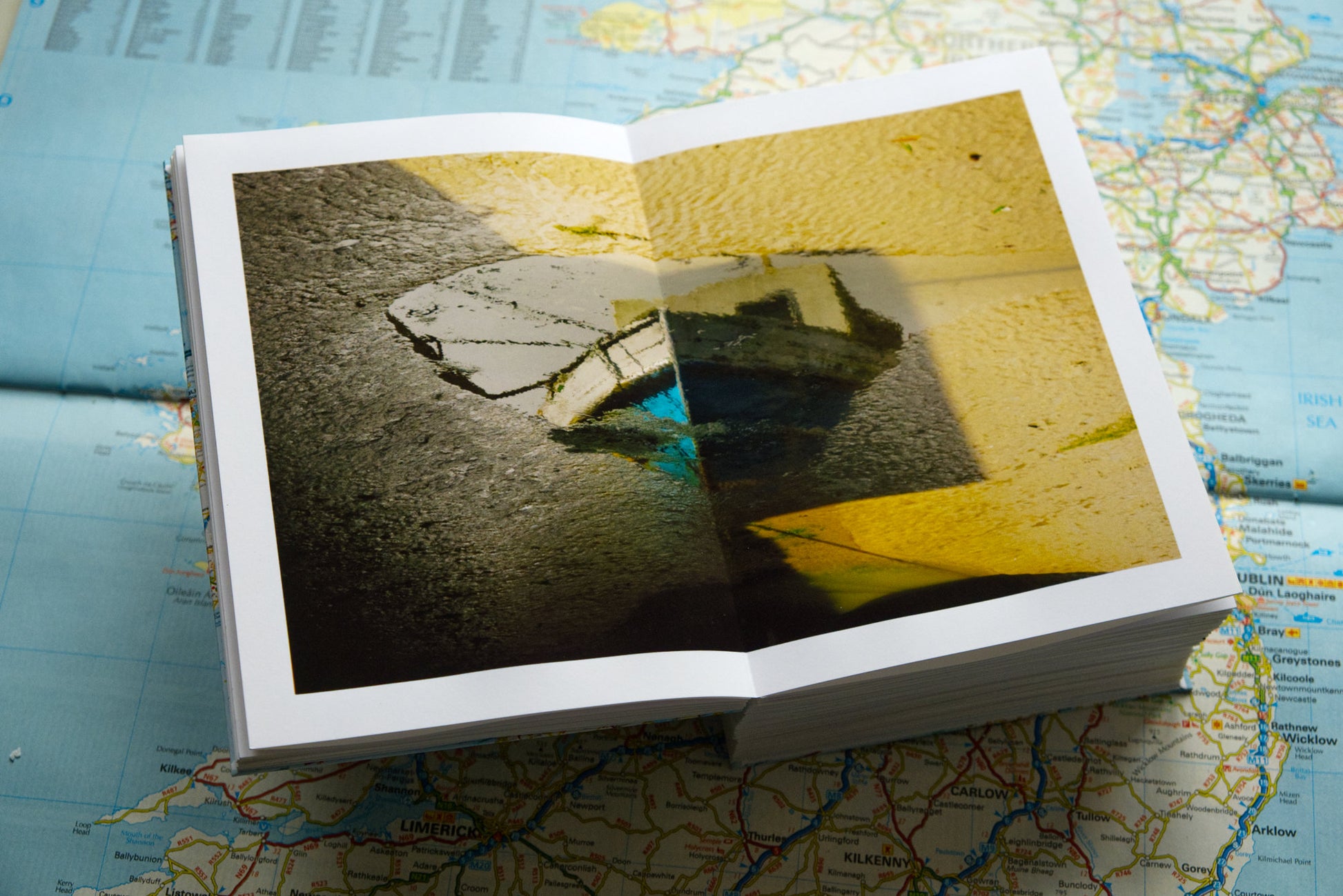 product photo of handmade photography book showing interior spread photograph of fishing boat reflected in puddle in sand at low tide